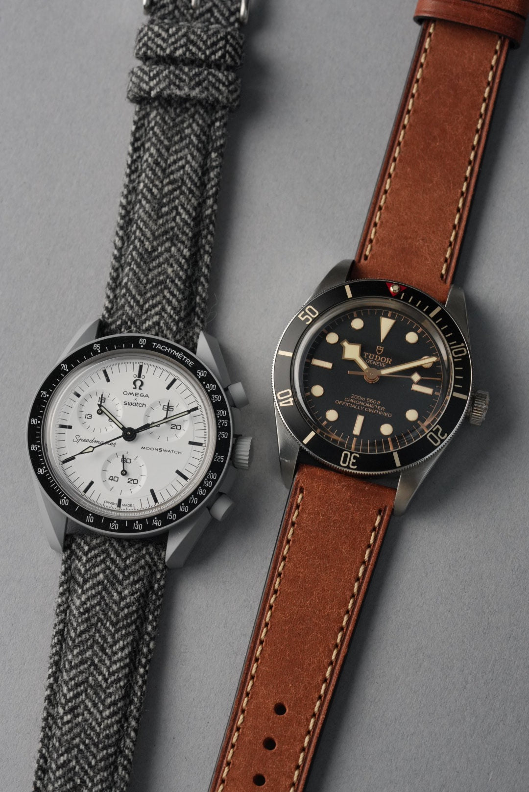 Two watches with different strap materials on a gray background
