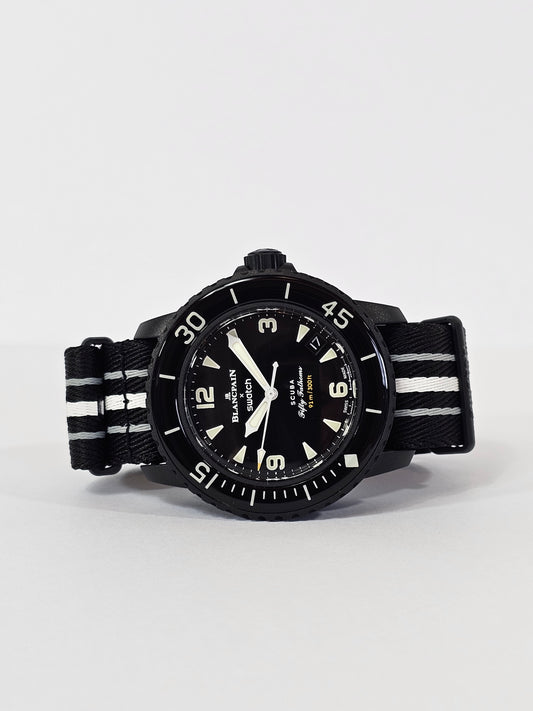 A black analog watch with a date display, a rotating bezel, and a strap made from recycled materials.