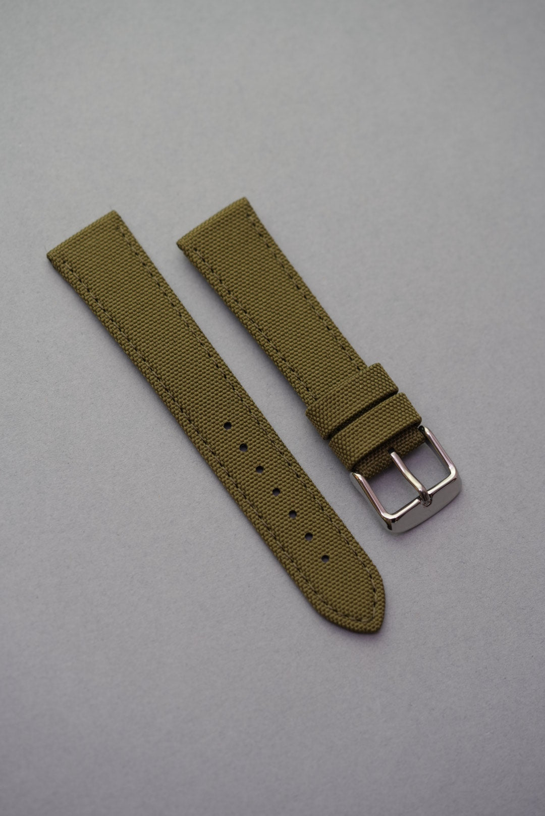 Military-style olive green canvas strap with textured weave and polished buckle, compatible with MoonSwatch.
