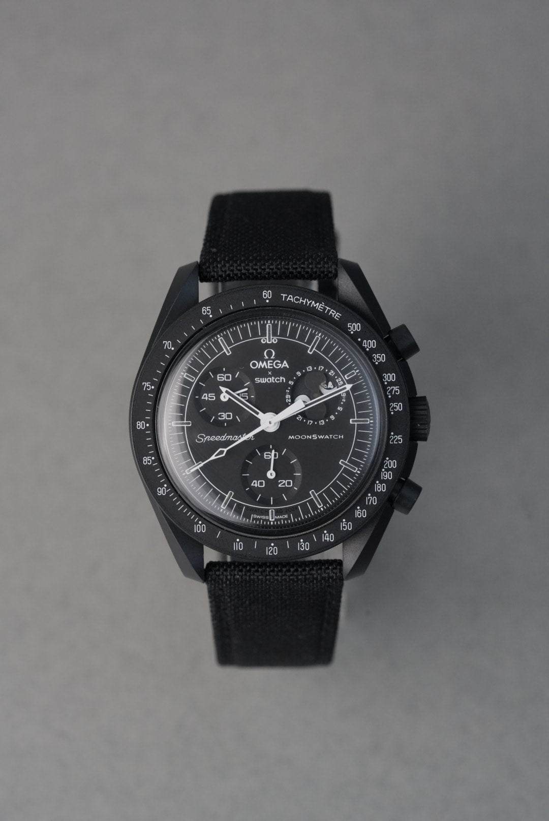 Black wristwatch with detailed face on a gray background