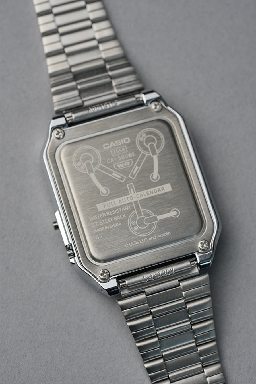 Silver Casio watch with a detailed face on a gray background. Flux capacitor motif Back To The Future