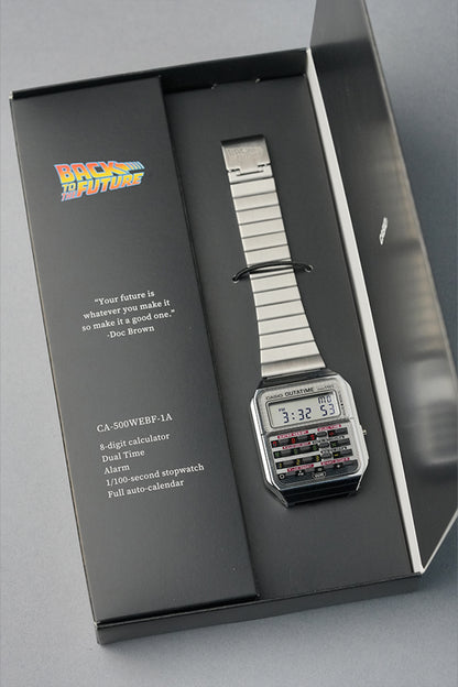 Wristwatch with a metallic band in a display case, featuring text and branding.