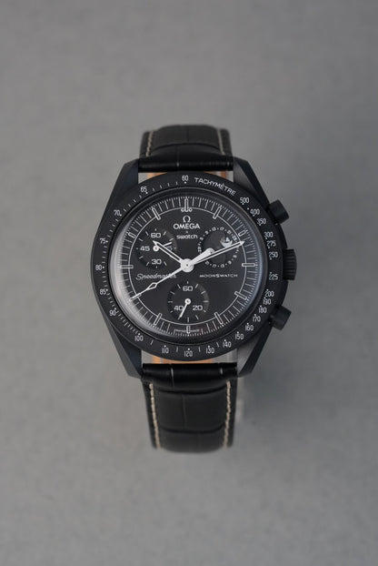 Black wristwatch with detailed face on a gray background
