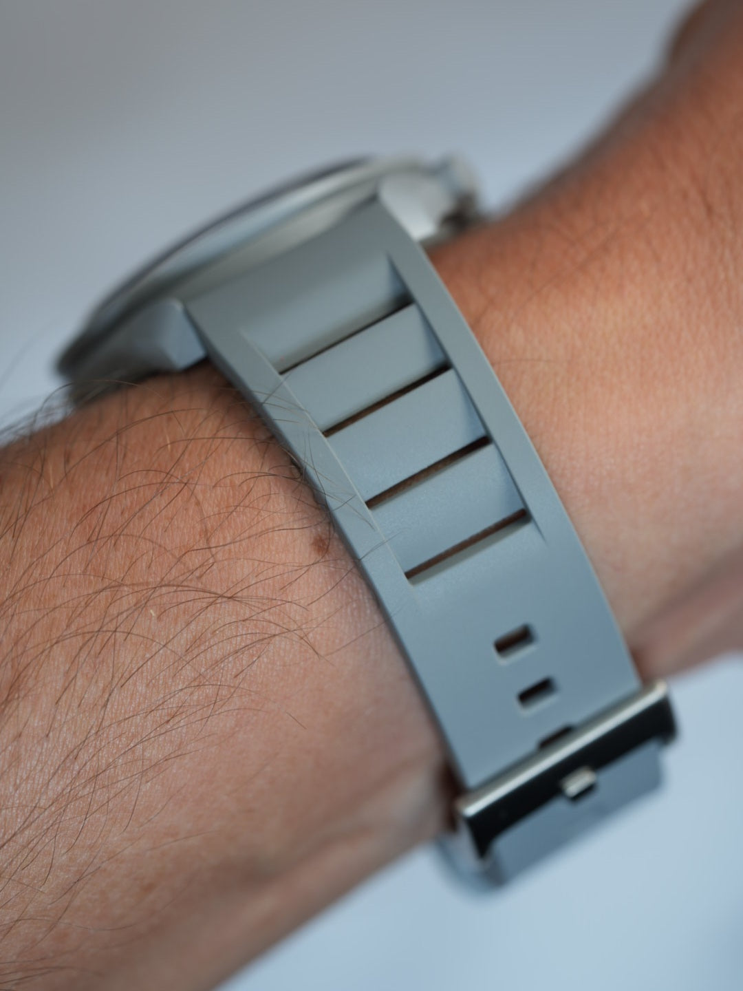 Close-up of the grey vented FKM rubber strap on a wrist, emphasizing its soft texture, flexibility, and sports-inspired design