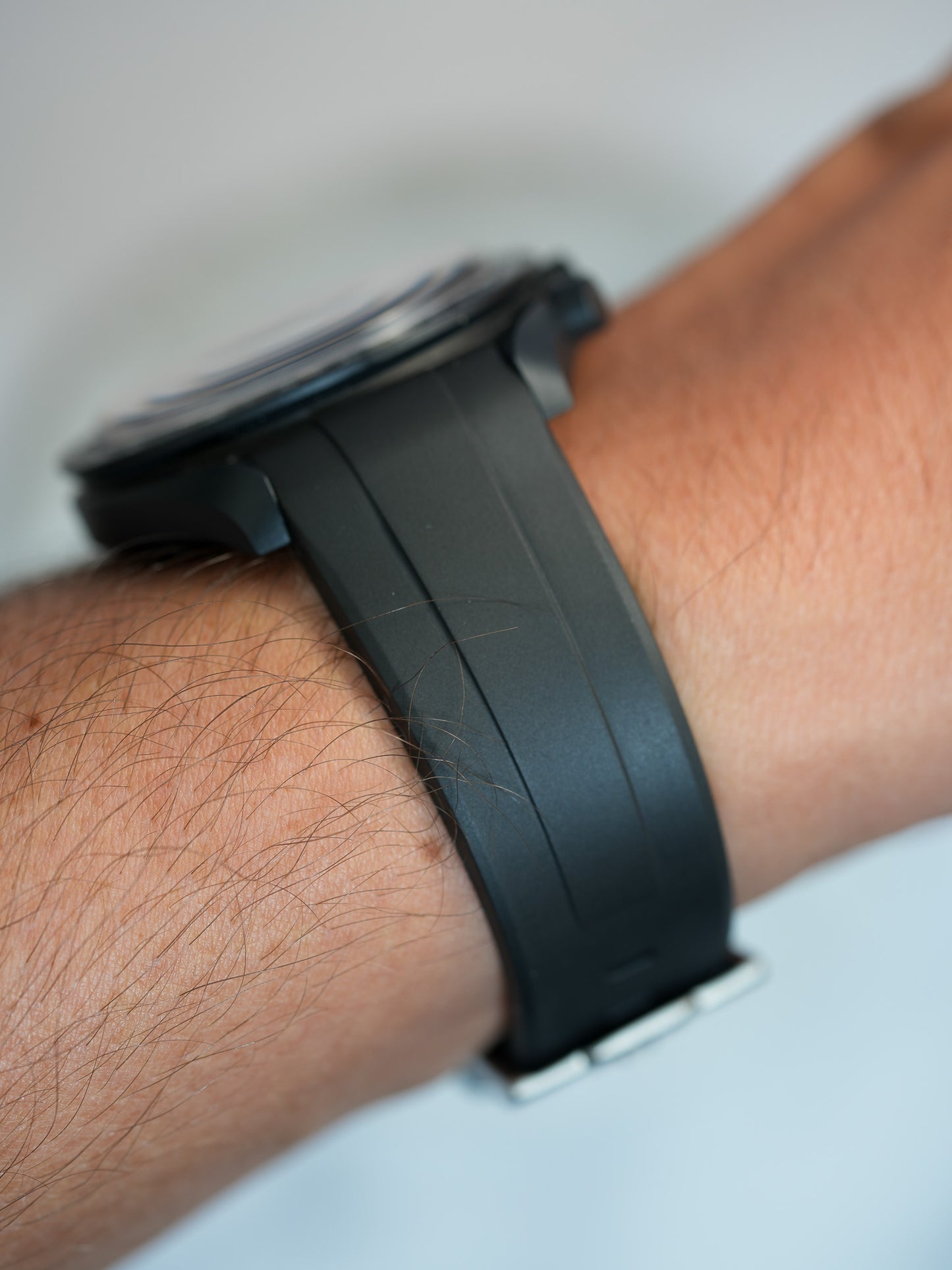 Close-up of curved-end black FKM rubber strap on wrist, offering a sleek and ergonomic fit for MoonSwatch, Rolex, or Tudor watches – waterproof and durable design.