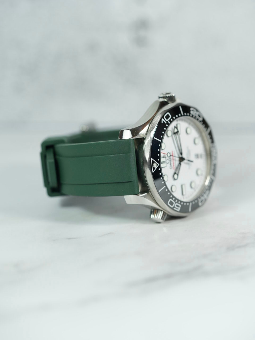 Side view of the Omega Seamaster on a wrist, highlighting the snug fit and smooth texture of the green FKM rubber strap.