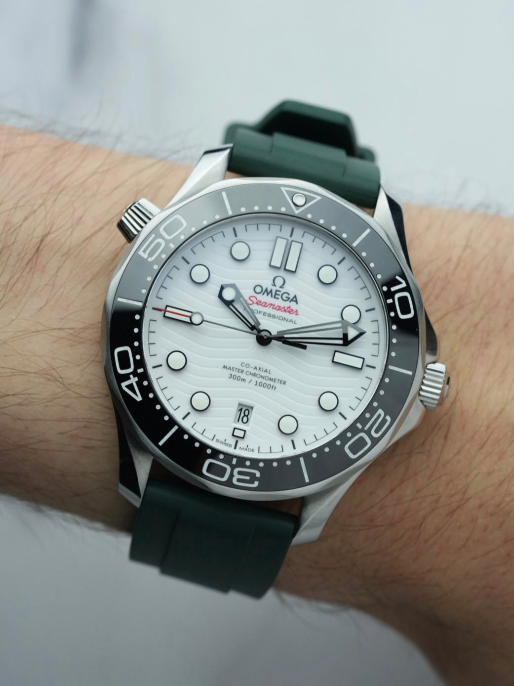 Wrist view of the Omega Seamaster, featuring the elegant green FKM rubber strap and the watch's detailed dial design with watch face showing