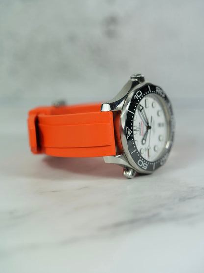 Side view of the Omega Seamaster on a wrist, highlighting the snug fit and smooth texture of the orange FKM rubber strap.