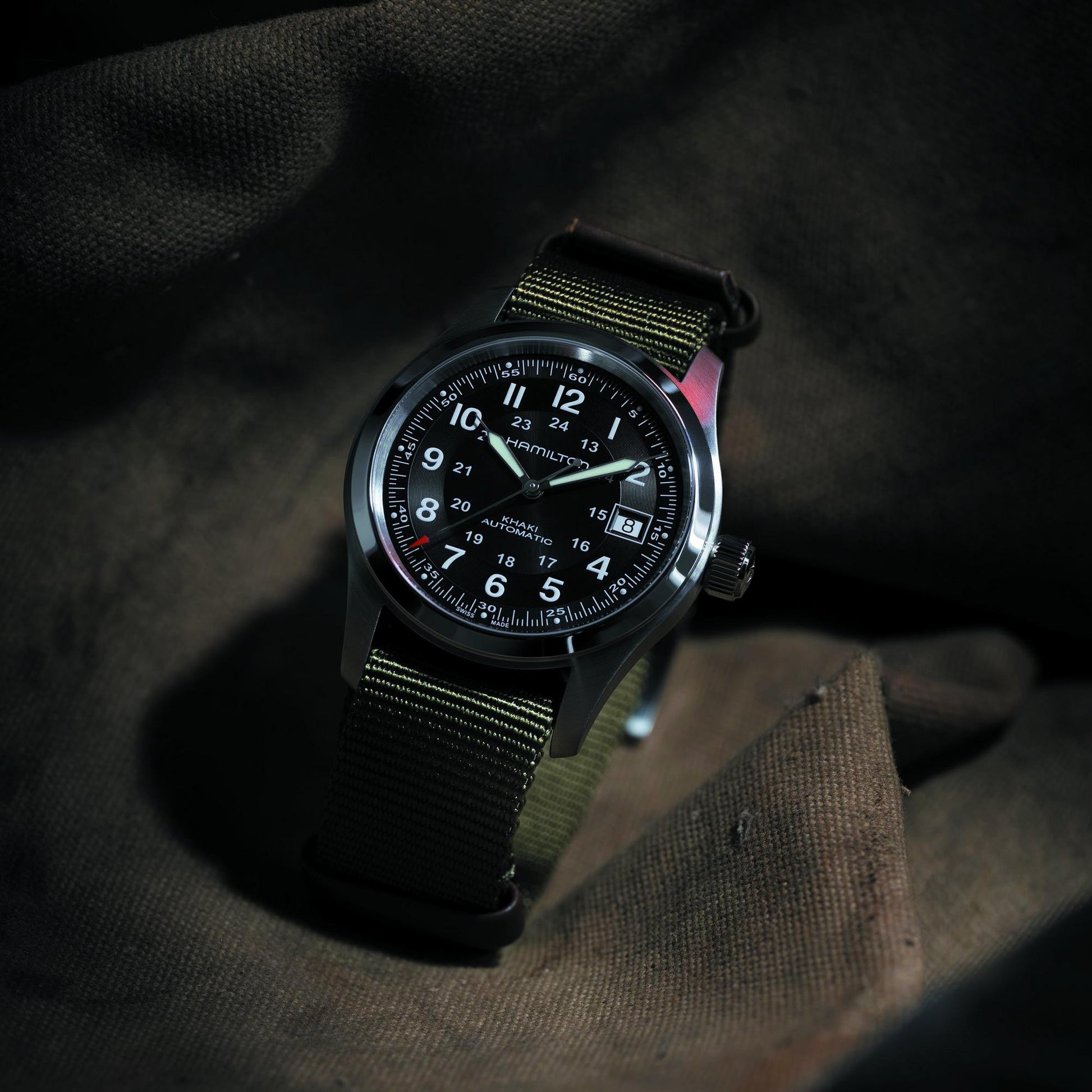 Black wristwatch with a detailed face on a dark fabric background