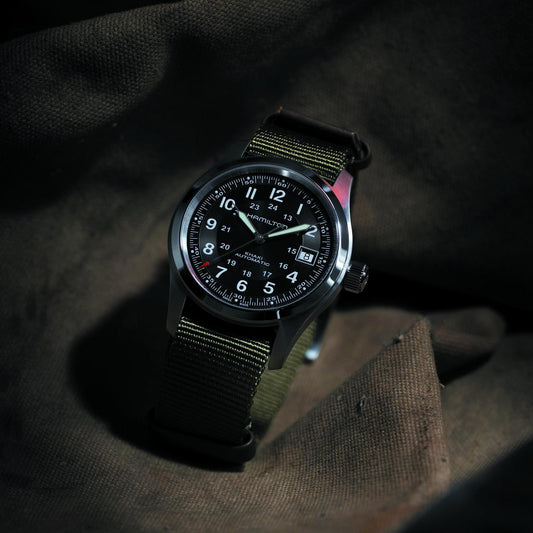 Black wristwatch with a detailed face on a dark fabric background