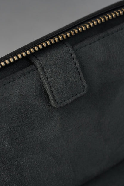 Close-up of a black leather jacket with a zipper detail on a gray background