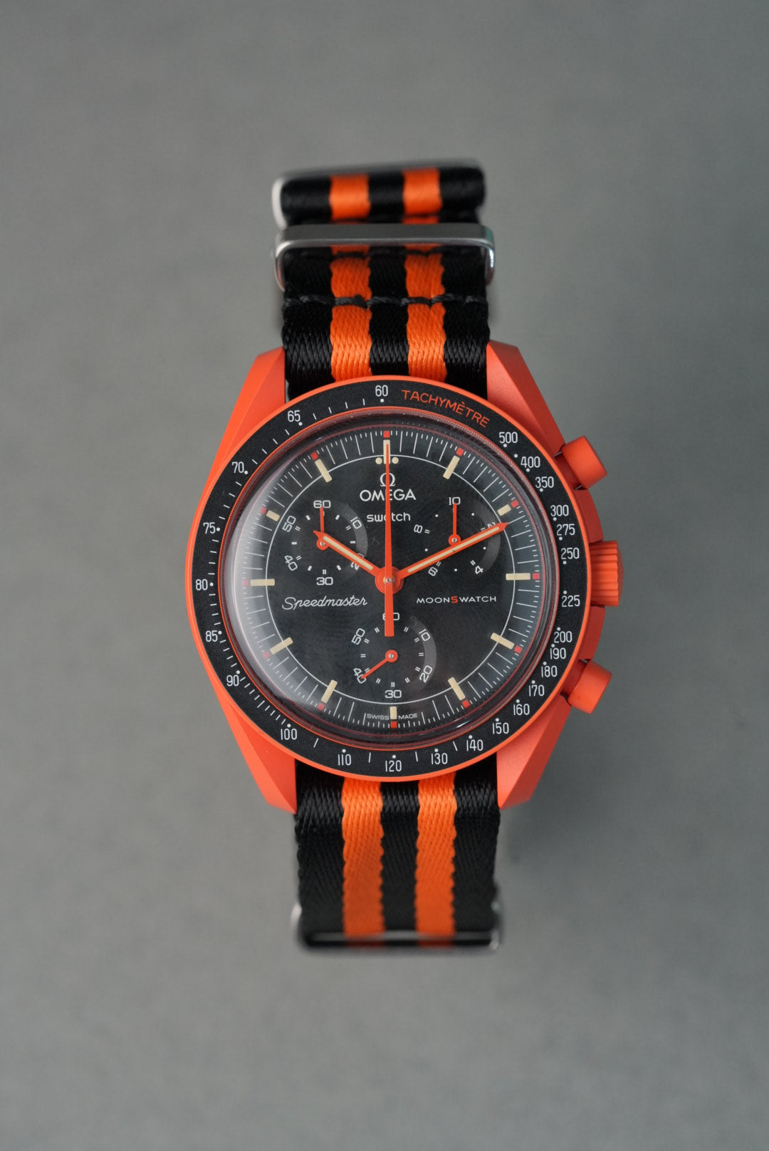 Omega watch with orange and black striped strap on gray background