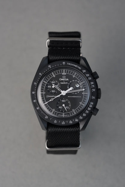 Black wristwatch with detailed face on a gray background