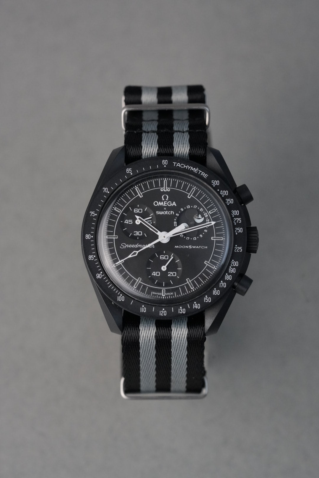 Black wristwatch with a striped strap on a gray background