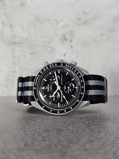 A black and white Omega X Swatch MoonSwatch watch strap with 007 Bond stripes, displayed on a watch face.