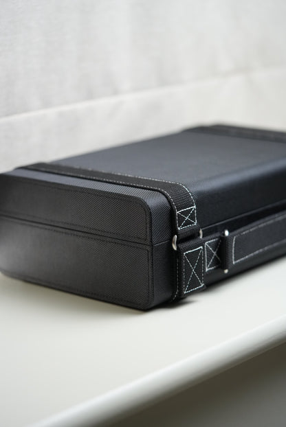 Close-up of a black suitcase with visible stitching details on a light gray background