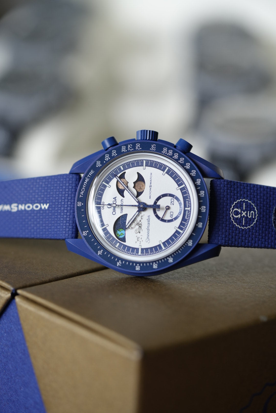 Blue Omega watch with detailed face on a blurred background