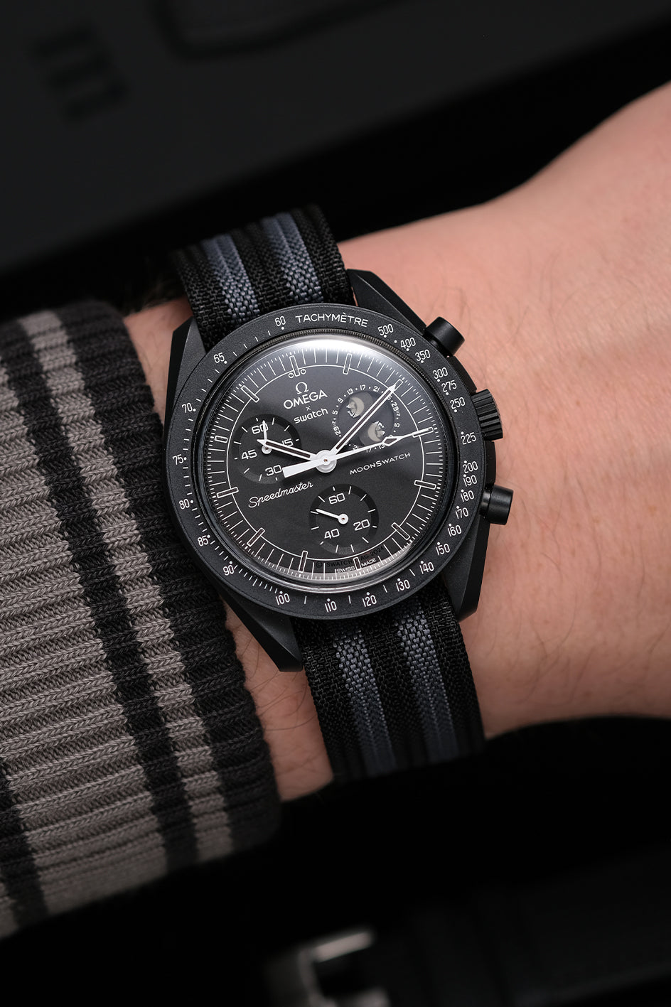 MoonSwatch nylon deployant strap on wrist — black and grey nylon on Snoopy New Moon MoonSwatch