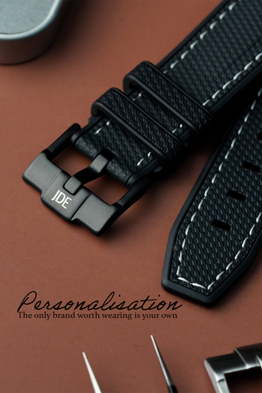 Black watch strap with 'JDE' branding on a brown background