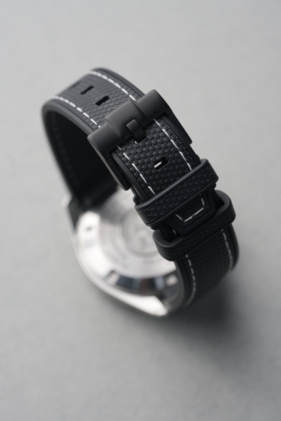 Close-up of a watch with a black strap on a gray background