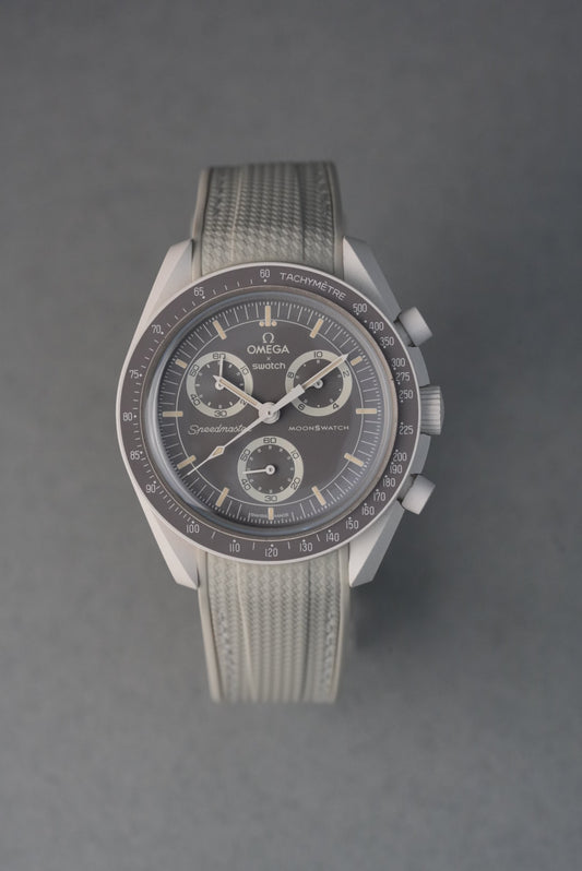 Beige rubber woven MoonSwatch strap with matching stitching and curved fit for a subtle, neutral aesthetic.