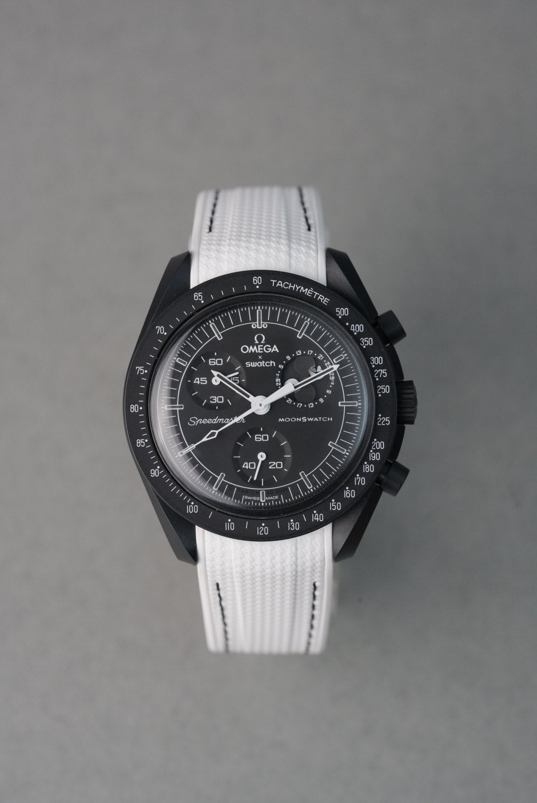 Wristwatch with a white strap and black dial on a gray background