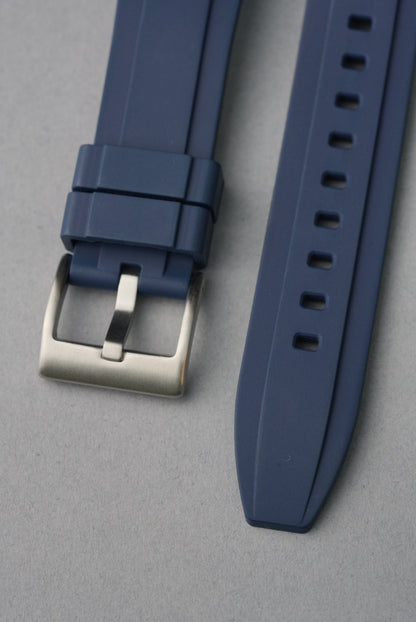 Blue watch strap with silver buckle on a gray background