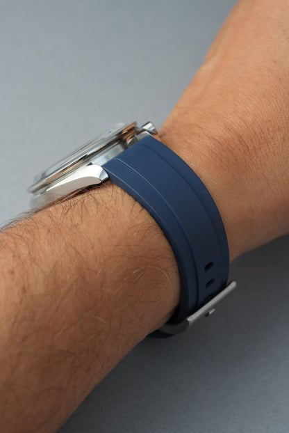Wrist wearing a watch with a blue band on a gray background