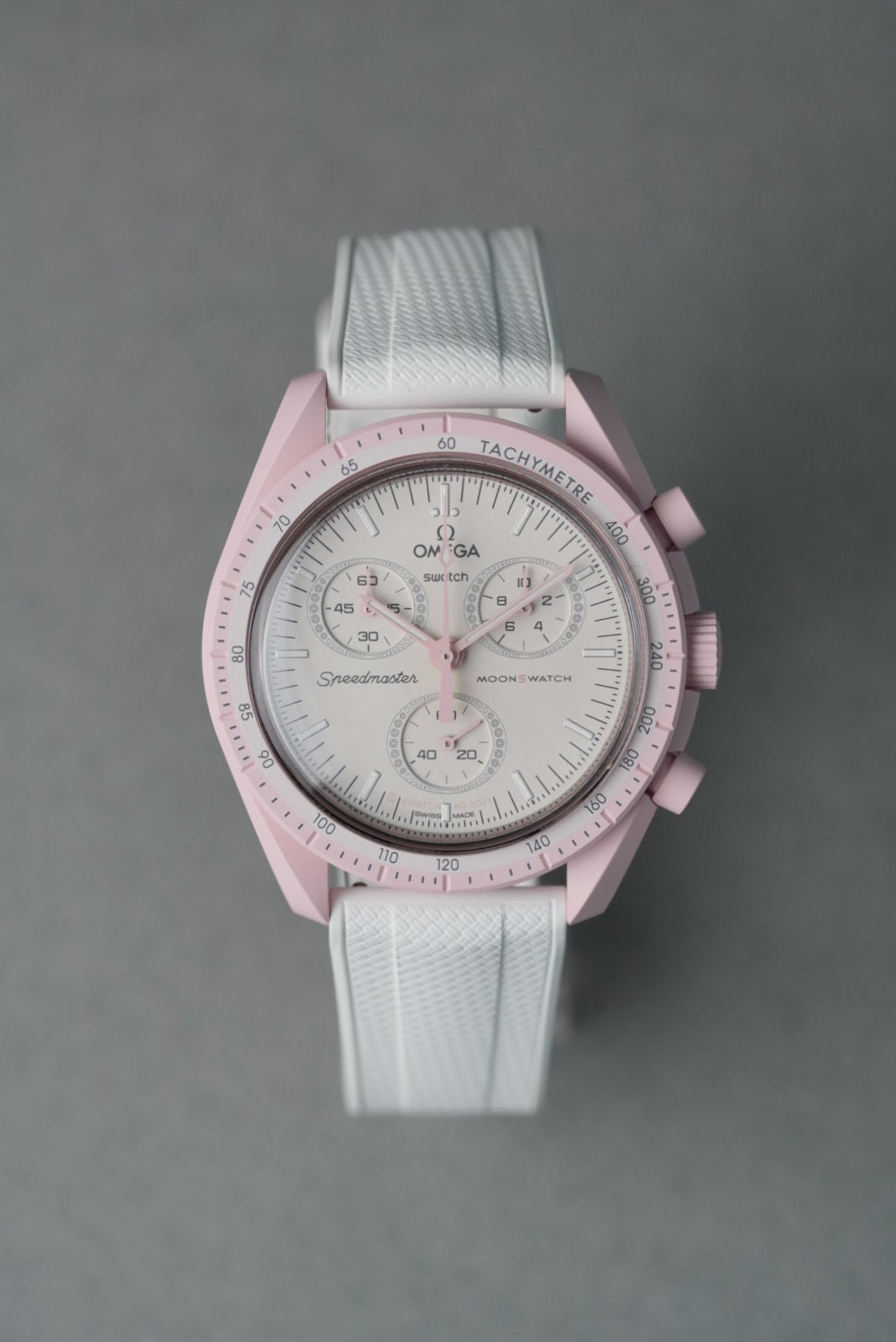 Pink watch with white strap on a gray background