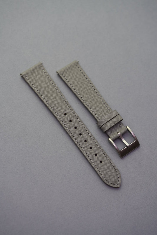 A gray Italian Saffiano leather watch strap with a buckle clasp, displayed on a gray background.