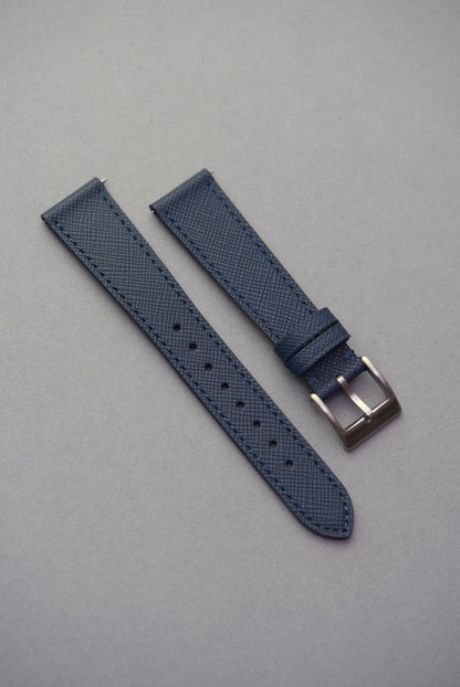 Blue watch strap with silver buckle on a gray background