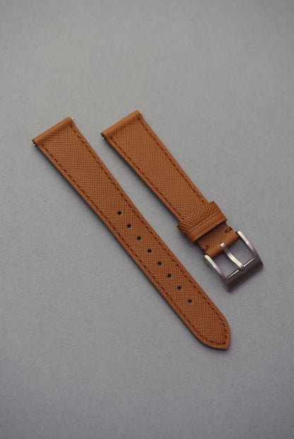 Brown watch strap with silver buckle on a gray background