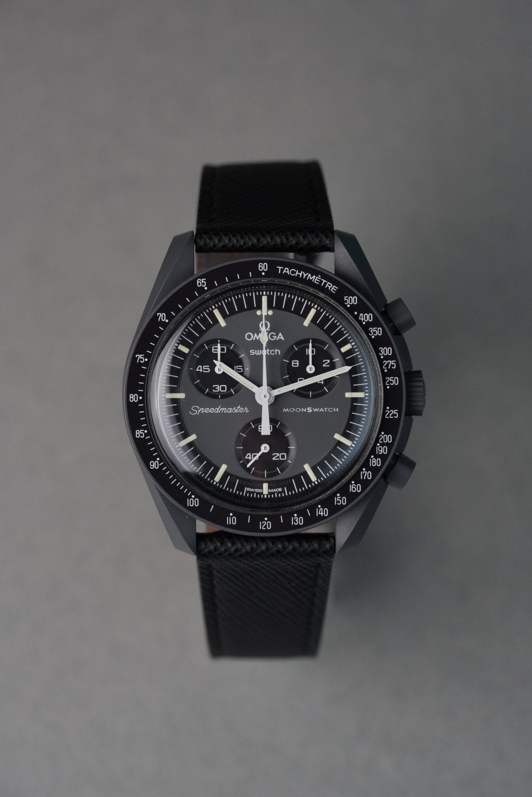 Black wristwatch with detailed face on a gray background