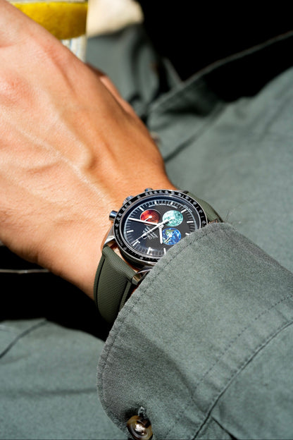 Close-up of a wrist wearing a detailed watch with a dark face and green strap.