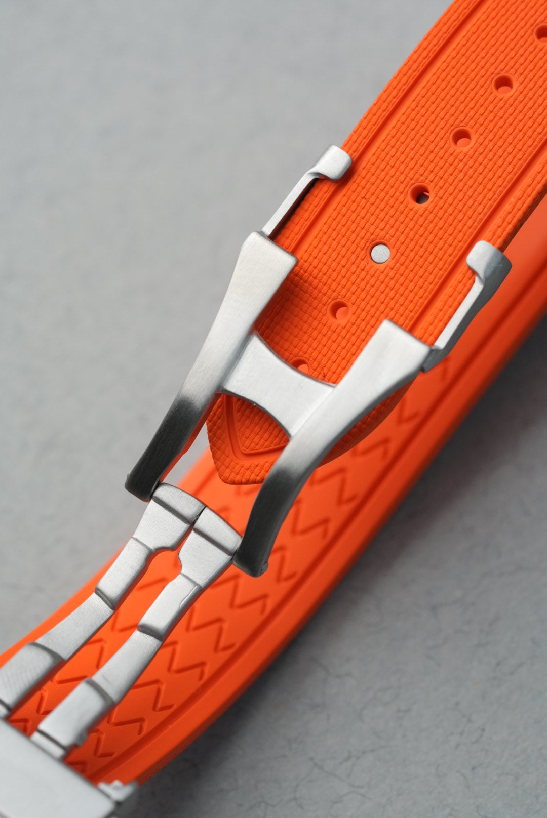 Close-up of an orange and white belt with a buckle on a gray background