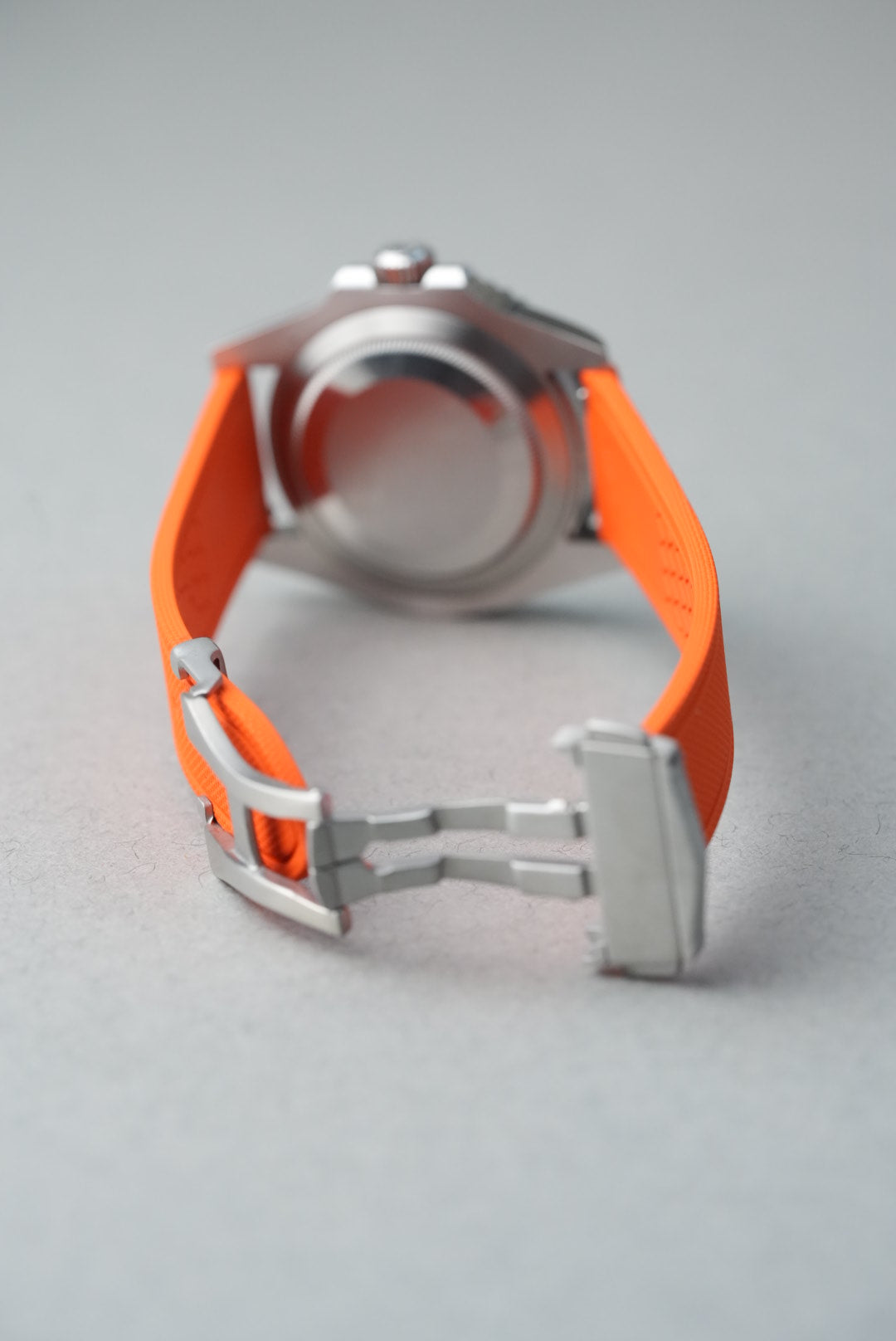 Close-up of a watch with an orange strap on a gray background