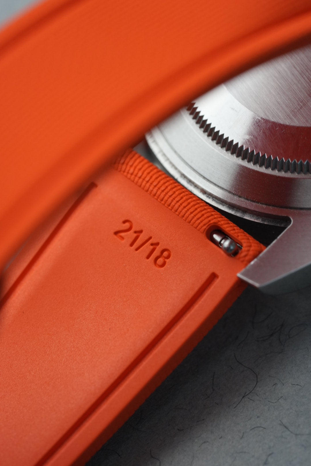 Close-up of an orange product with a silver component and '21/18' marking.