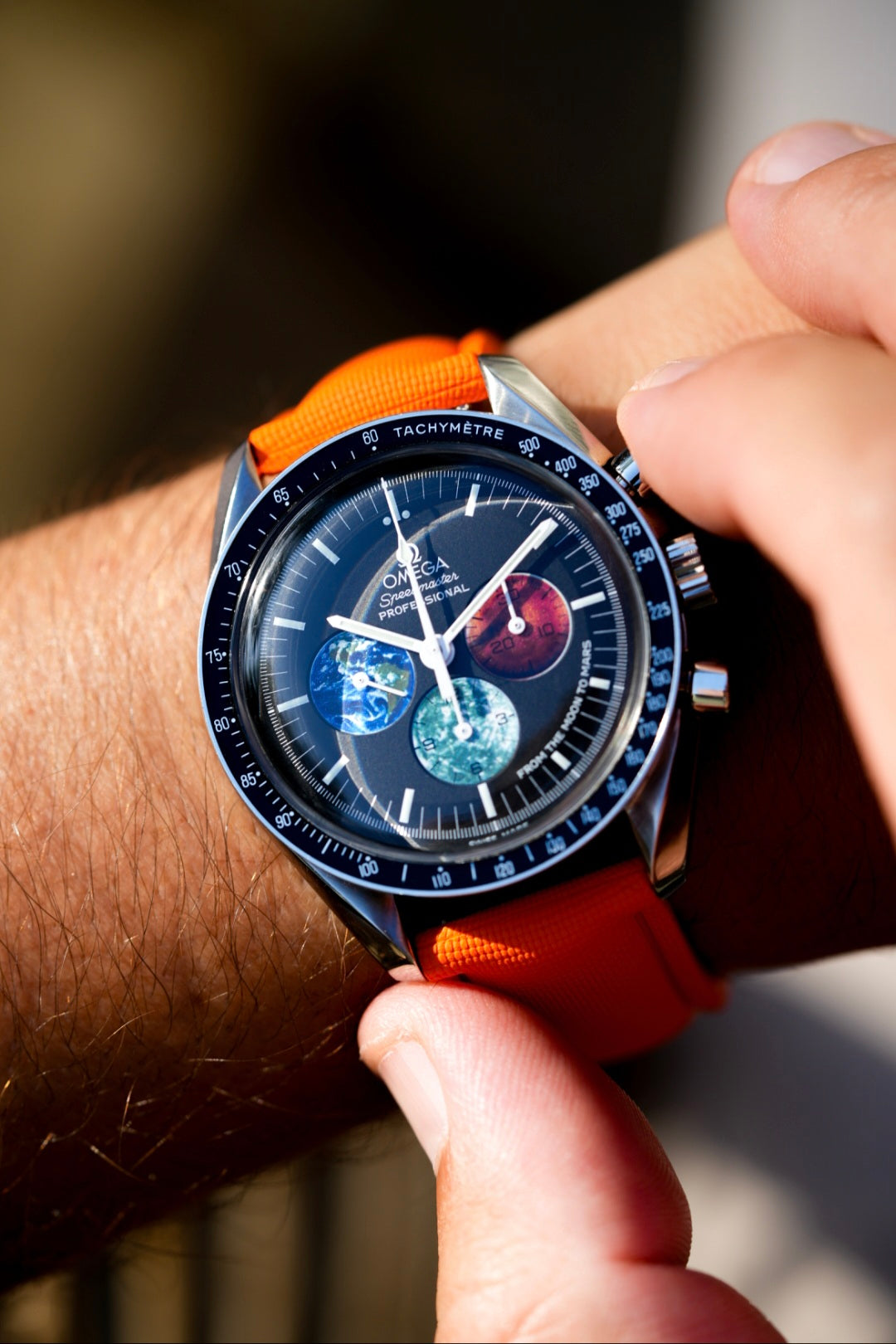 Close-up of a wrist wearing a watch with an orange strap and detailed face.