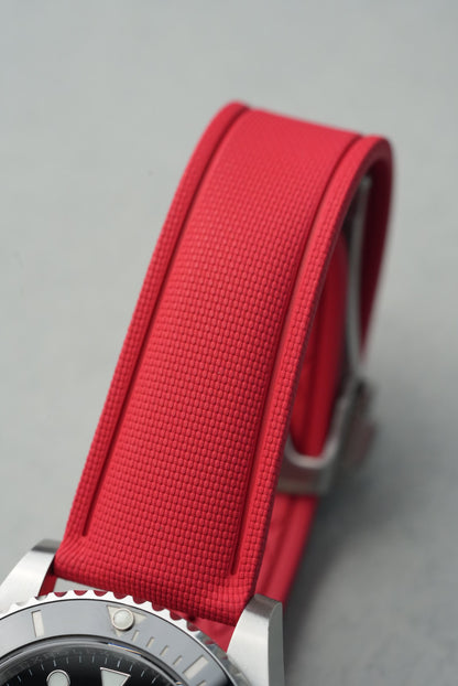 Close-up of a watch with a red strap on a gray background