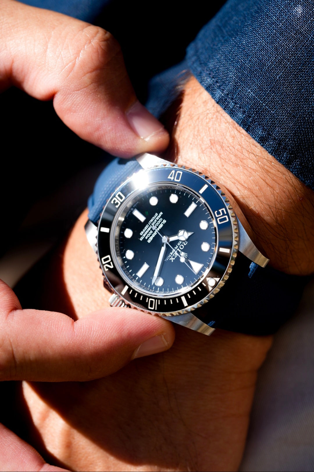 Close-up of a person wearing a blue wristwatch with a dark face.