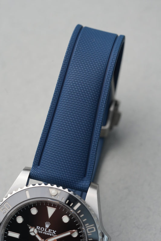 Rolex watch with a blue strap on a gray background
