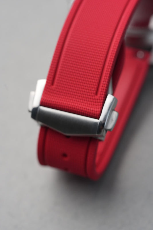 Close-up of a red belt with a silver buckle on a gray background