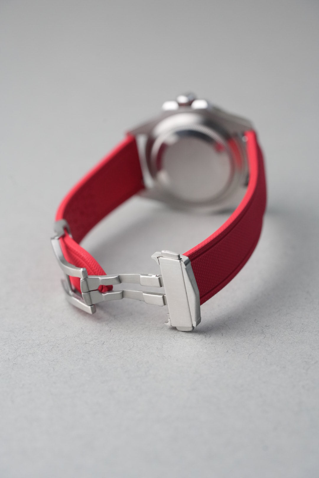 Close-up of a watch with a red strap on a gray background