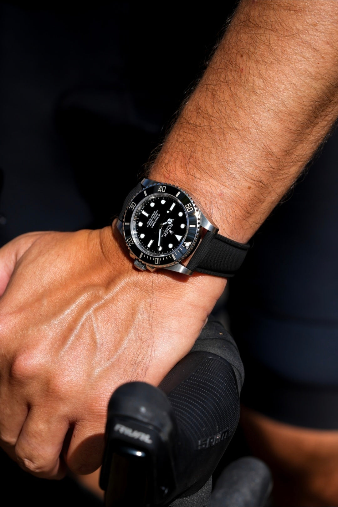 Close-up of a person's wrist wearing a black wristwatch with a blurred background
