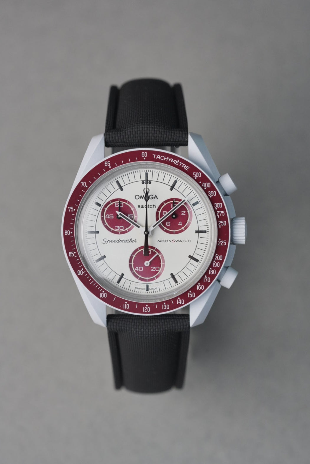 Omega watch with black strap and red accents on a gray background