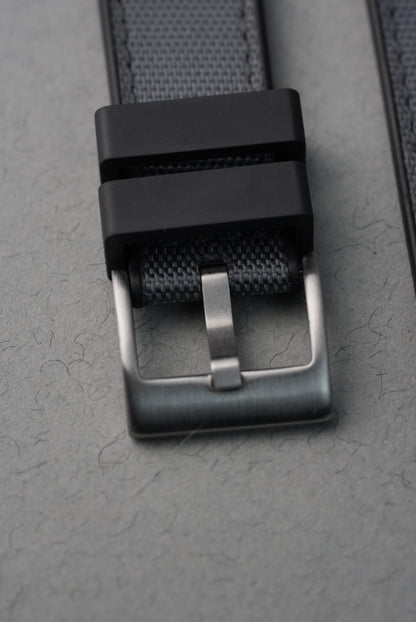 Close-up of a black belt with a silver buckle on a gray textured background