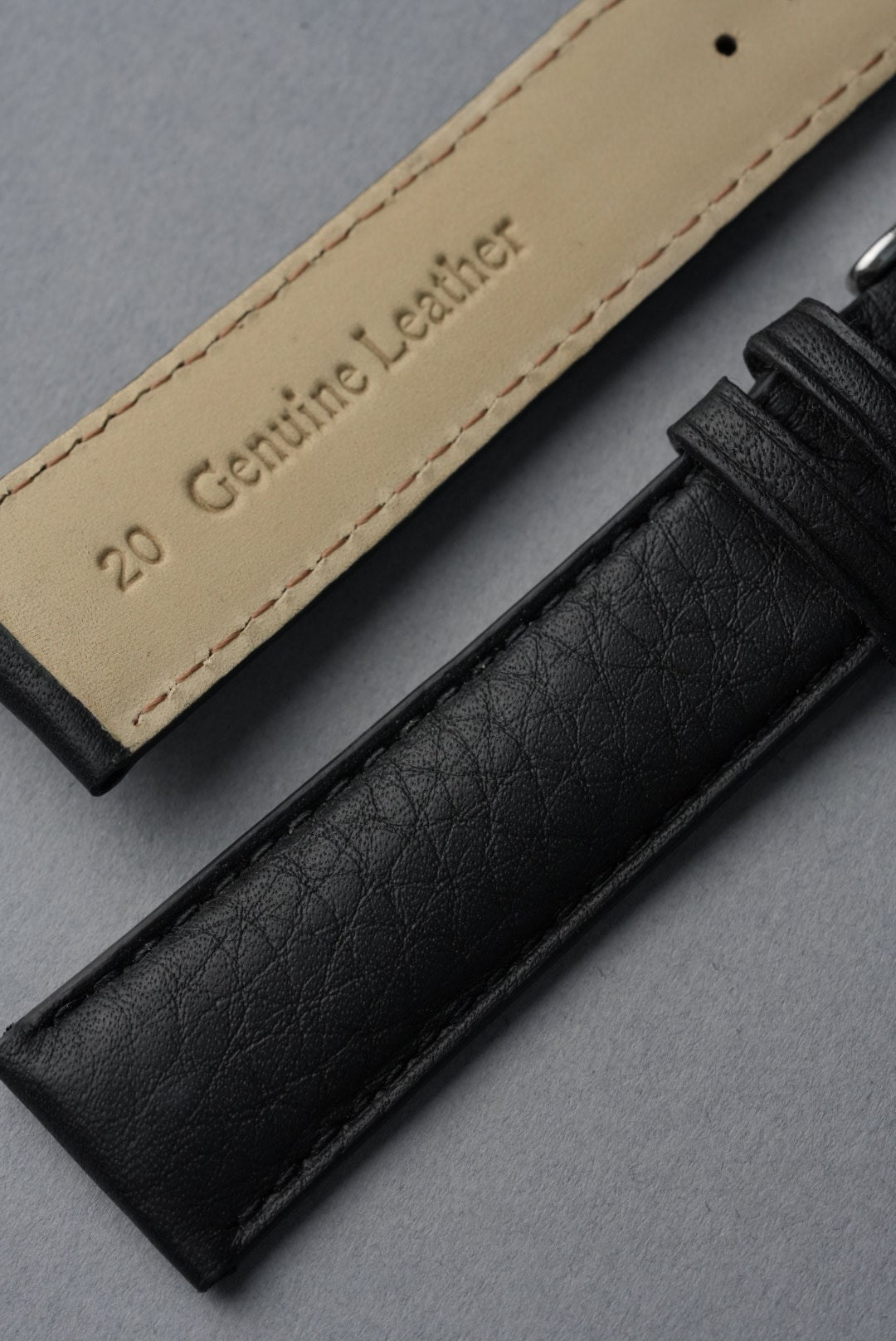 Black and beige leather straps with 'Genuine Leather' text on a gray background