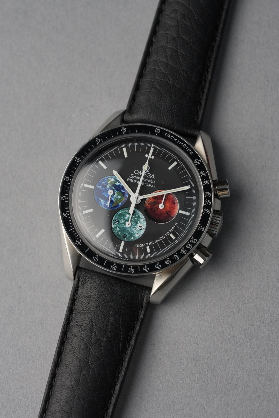 Watch with a unique face featuring Earth, Moon, and Sun designs on a gray background