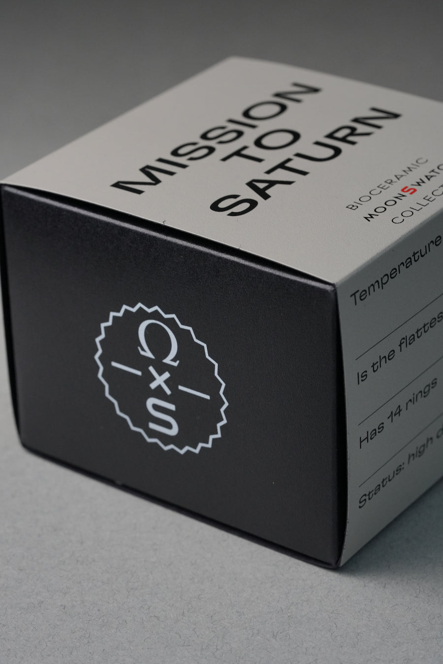 Product packaging with 'Mission to Saturn' text and Omega logo on a gray background