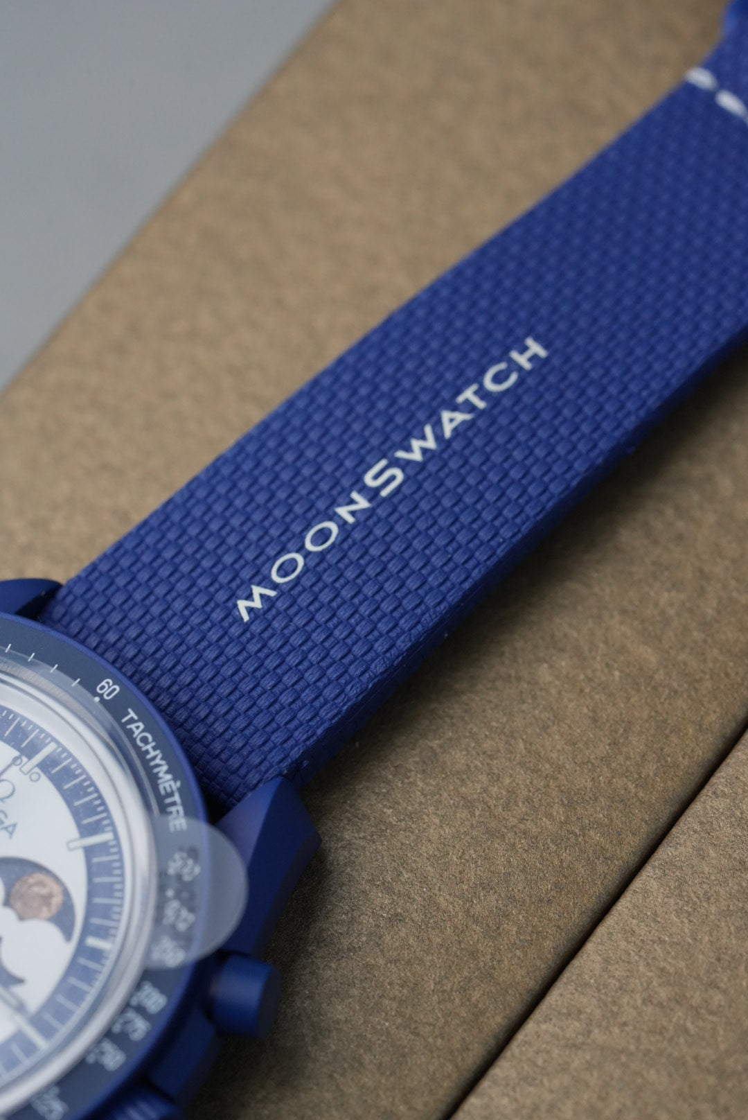 Moonswatch watch with blue strap on a brown textured background